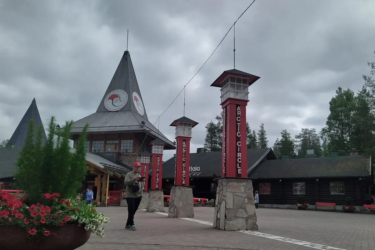 Row of red Arctic Circle marker towers in front of the Santa Claus Village buildings