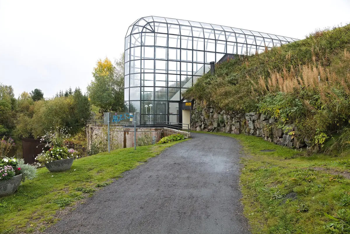 Glass tunnel of the Arktikum museum with a gravel path and grassy slope