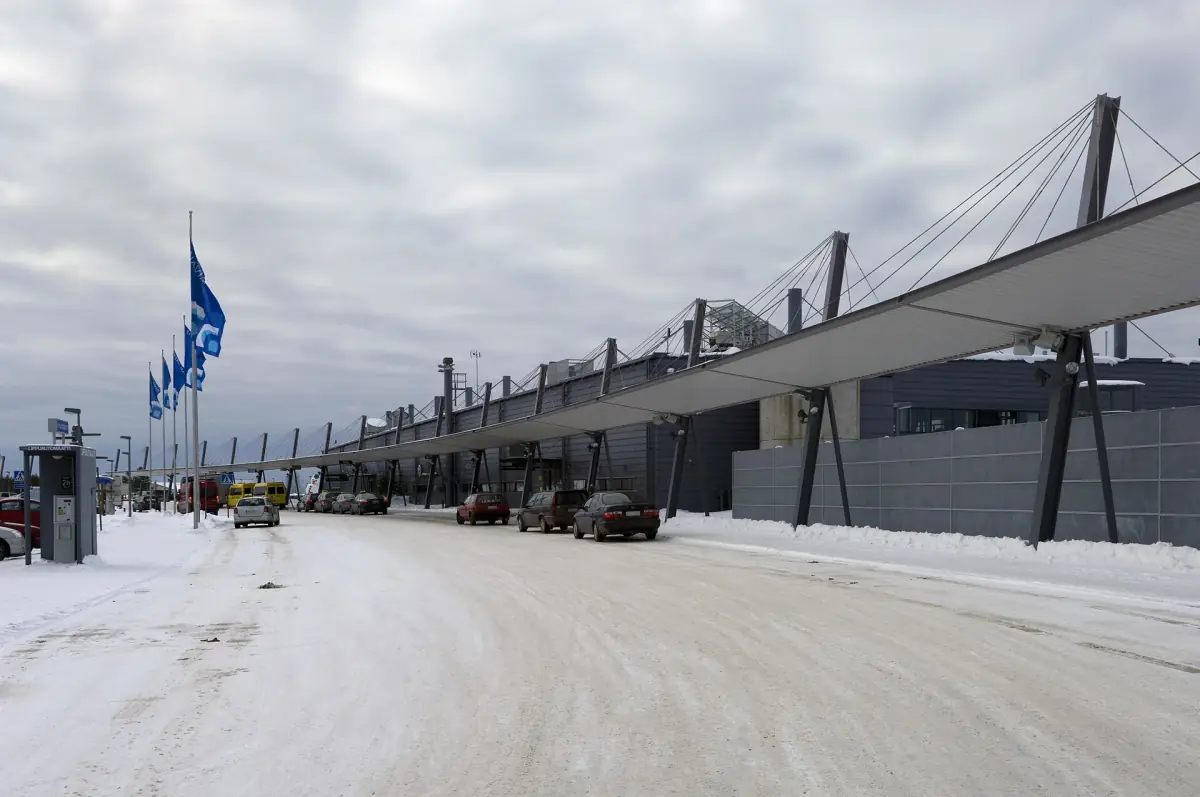 Rovaniemi Airport terminal with its bridge-like roof beside a snowy road in winter