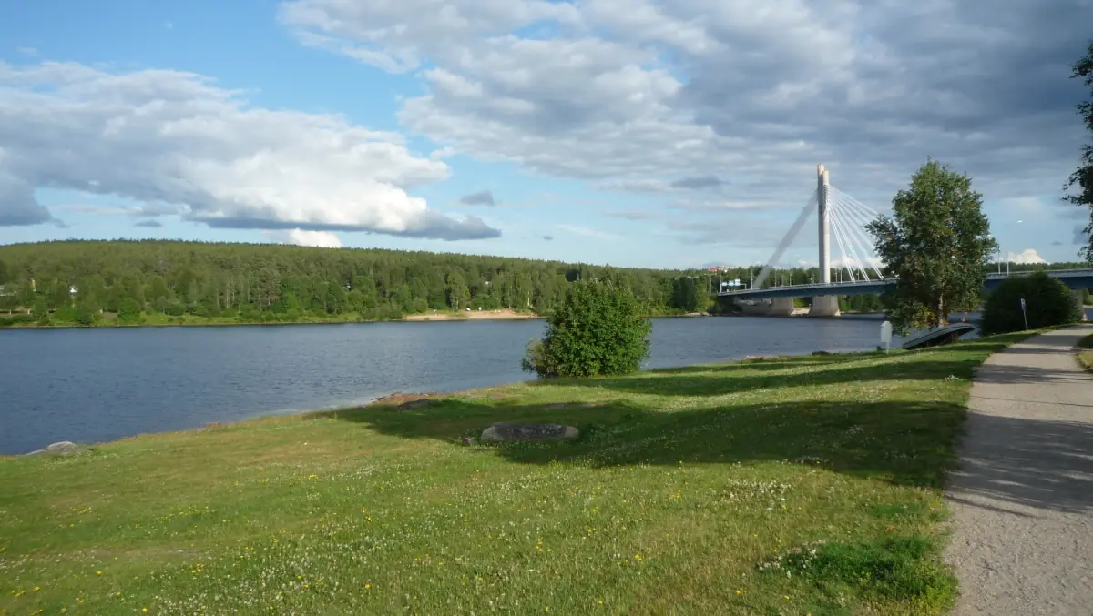 Lumberjack's Candle Bridge over the Kemijoki river with green riverbank in Rovaniemi