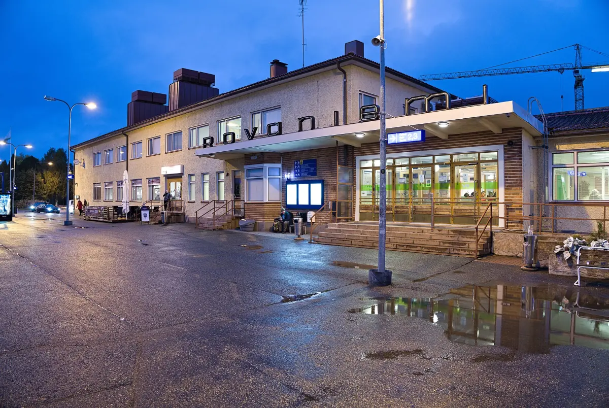 Rovaniemi railway station building lit at dusk with wet pavement
