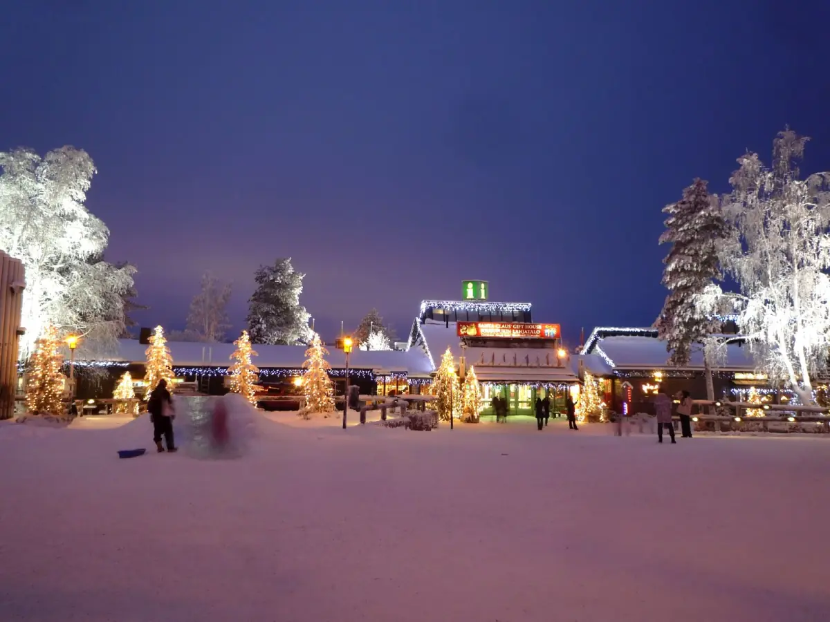Santa Claus Village square in blue evening light with illuminated trees and cabins