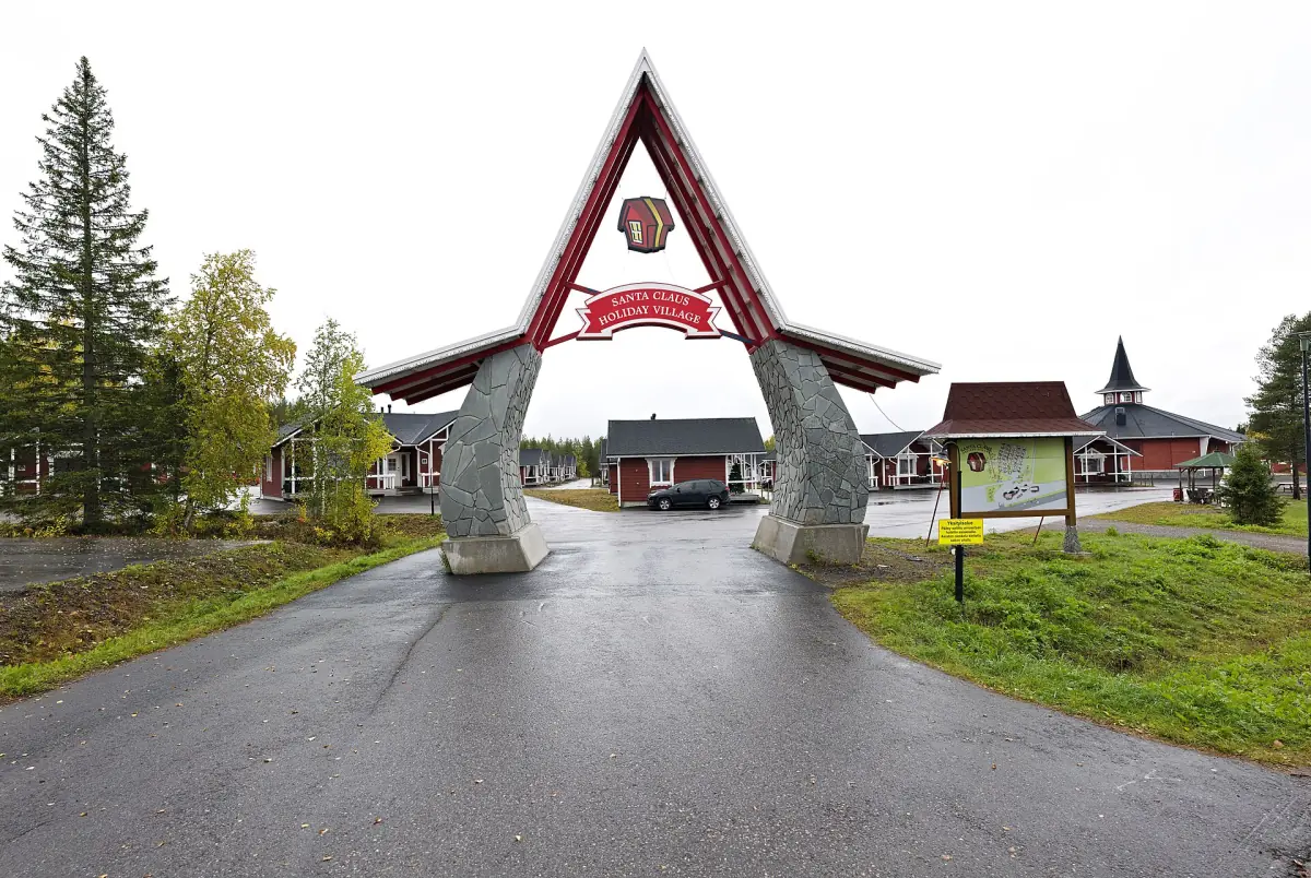 Red and white entrance arch with stone pillars leading into Santa Claus Village